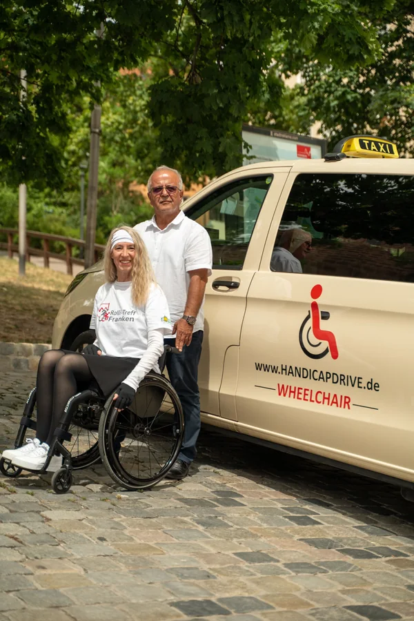 Fahrgast und Fahrer am barrierefreien Taxi von Handicap Drive